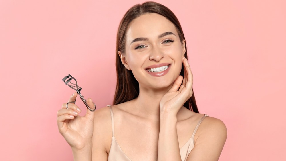 A woman holding an eyelash curler