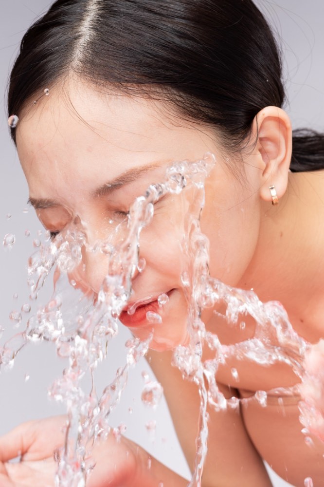Woman washing her face with water
